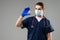 Male doctor with surgical mask, goggles and protective suit holding blood samples on gray backround. Vials with cure Covid-19