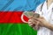 Male doctor in uniform on the background of the silk national flag of Azerbaijan is holding dollars, money, the concept of