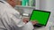 Male doctor uses a laptop with a green screen chroma key for work and typing. Telemedicine, telehealth concept. Remote