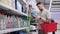male driver is choosing engine oil in supermarket, reading label on plastic bottle