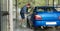 a male driver cleaning the car inside the self wash station box