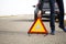 a male driver puts a red triangle warning sign on the road as a symbol of a car breakdown