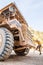 Male driver walks up the stairs of large quarry dump truck, production useful minerals, to transport coal from open pit in