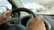 Male driving a car, his hands on steering wheel against windshield, close-up