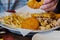 Male eating assorted fried seafood and french fries on a white plate