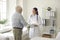 Male elderly patient and woman physician handshaking at modern clinic office