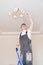 A male electrician changes the light bulbs in the ceiling light.