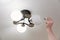 A male electrician changes the light bulbs in the ceiling light.