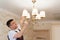 A male electrician changes the light bulbs in the ceiling light.