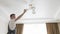 A male electrician changes the light bulbs in the ceiling light.