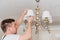 A male electrician changes the light bulbs in the ceiling light.