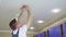 A male electrician changes the light bulbs in the spotlight ceiling lamp