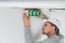 Male electrician fixing electric sign on ceiling