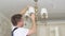 A male electrician repairs ceiling lamp.