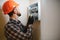 A male electrician works in a switchboard with an electrical connecting cable