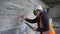 A male engineer in a construction helmet and antiviral mask inspects an emergency building for restoration or repair.