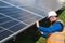 Male engineer fixes solar panels to a metal frame using bolts and electric wrench.