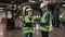 Male Engineer Holding Tablet and Explaining Tasks to Woman Contractor at Warehouse