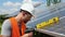 Male engineer in protective helmet installing solar photovoltaic panel system using screwdriver. Electrician mounting