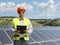 Male engineer standing in front of solar panels in a field and looking to the side