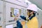 Male engineer wearing a yellow uniform and wearing a white safety hat, inspecting electrical systems in a large power plant