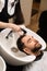 Male enjoys washing hair in barbershop