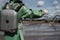 A male environmentalist in a green protective suit and gas mask takes a sample of water in a polluted lake for research