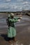 A male environmentalist in a green protective suit and gas mask takes a sample of water in a polluted lake. Waste from