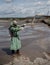 A male environmentalist in a green protective suit and gas mask takes a sample of water. The scientist is doing a