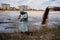 A male environmentalist in a protective suit and gas mask takes a sample of water. Scientist doing toxicological study.