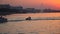 A male extreme on a hydrocycle rides near a slow boat against the background of the city embankment during sunset, slow