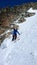 Male extreme skier skiing down a very steep couloir in deep winter in the Swiss Alps near Klosters