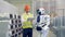 Male factory employee is explaining something to a robot and regulating its settings