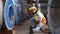 A male factory worker assists a female industrial worker who has an injured leg.