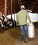 Male farmer carries a large milk can in his hands at cow farm