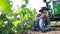 A male farmer is talking on a mobile phone in a field near a tractor.