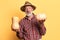 Male farmer with wrinkles and gray beard, stands with pumpkins in both hands