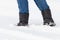 Male feet in black boots, winter walking in snow