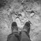 Male feet in shoes stand on dirty dusty road