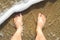 Male feet standing on the beach watching the water waves view from above