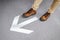 Male feet stepping over arrowhead sign on the floor