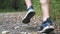 Male feet of young athlete running along trail in early autumn forest. Legs of sporty man jogging along path at nature