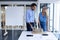 Male and female architect discussing over architectural model at table in a modern office