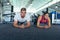 Male and female athletic performing plank exercise in fitness center