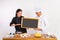 male and female chefs showing blank blackboard standing near table