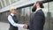 Male and female colleagues shaking hands in street, business cooperation meeting