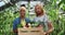 Male and female farmers holding box of colourful vegetables and greenery and smiling. Different race man and woman