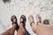 Male and female feet in open shoes, sandals. View from above. They stand on dry ground with cracks, a little dried grass