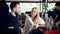 Male and female friends in cafeteria sitting at a bar counter in summer day with barman working.Beautiful girl telling