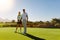 Male and female golfers at field on sunny day